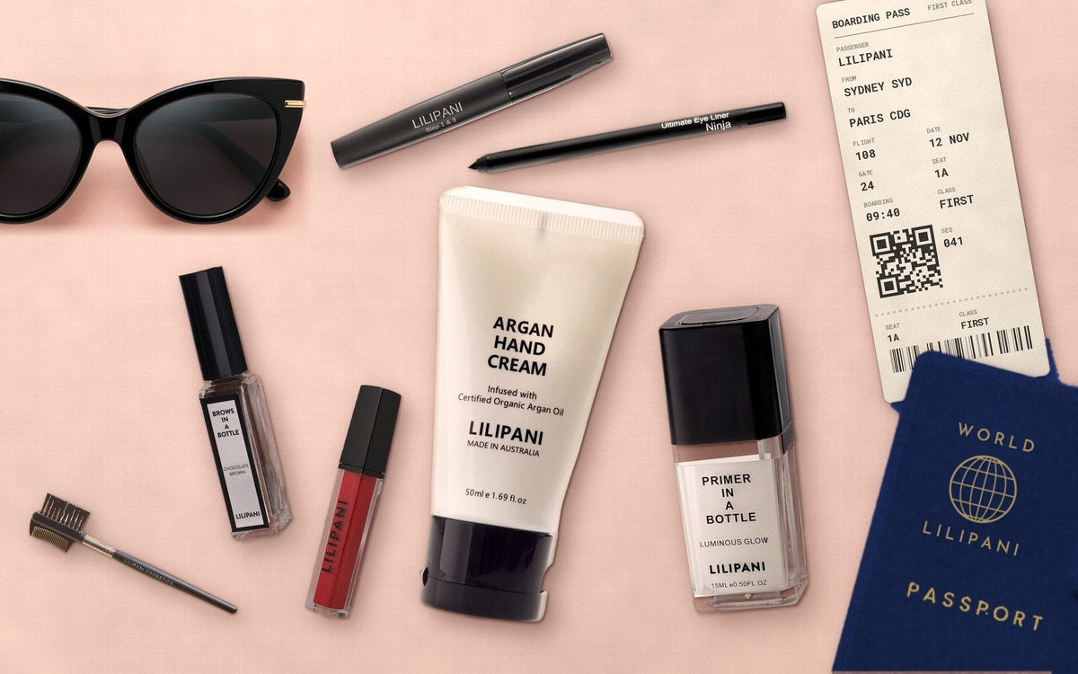 LILIPANI travel makeup flat-lay with navy passport, boarding pass and travel-size makeup